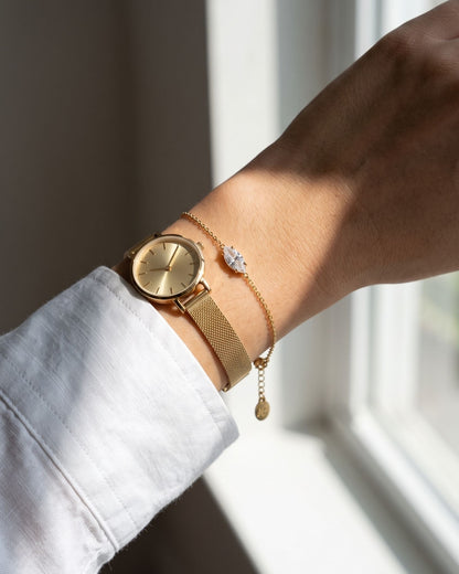 Petite rhinestone charm bracelet styled on a wrist alongside a minimalist watch and white linen shirt.