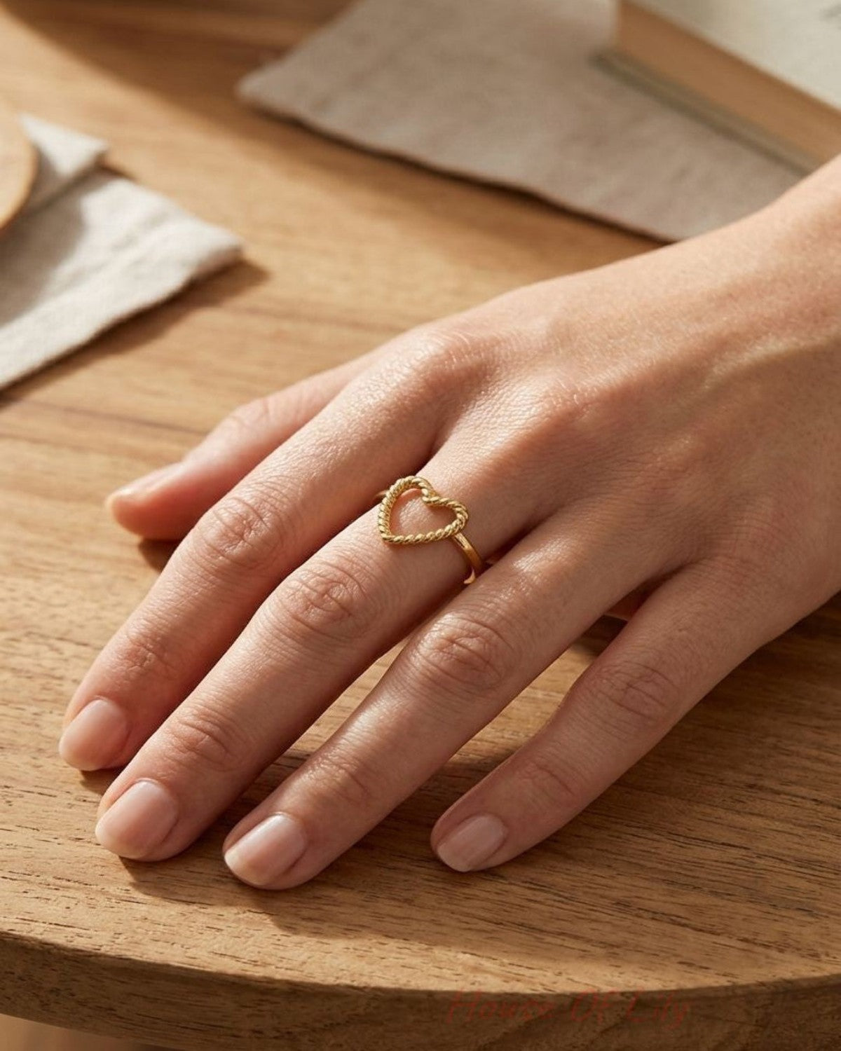 Small stainless steel heart ring, 2cm high, resting on a wood surface, highlighting its minimalist design and polished finish.