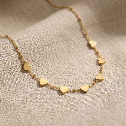 Stainless steel Heartbeat Chain necklace displayed on beige textured fabric, emphasizing its slim profile and everyday style.