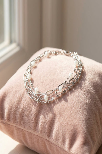 Close-up of a three-layered gold stainless steel bracelet with colored details on a velvet cushion.