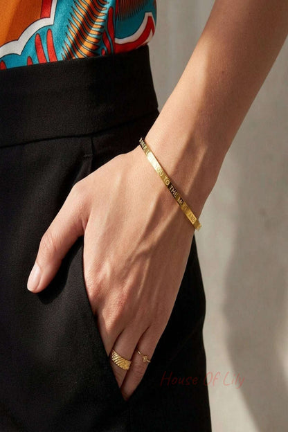 Small slave bracelet with 'love you to the moon and back' inscription, showcasing micro-texture on neutral fabric.