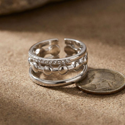 Close-up of layered Triple Tier Sparkle Ring with rhinestones on textured surface, highlighting its elegance and irregular shape.
