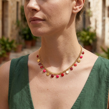Close-up of a small red enamel coin pendant necklace on a woman's neck, highlighting its irregular circular shape and stainless steel craftsmanship.