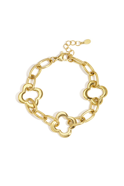 Gold chain link bracelet with three clover-shaped links laid flat on white background