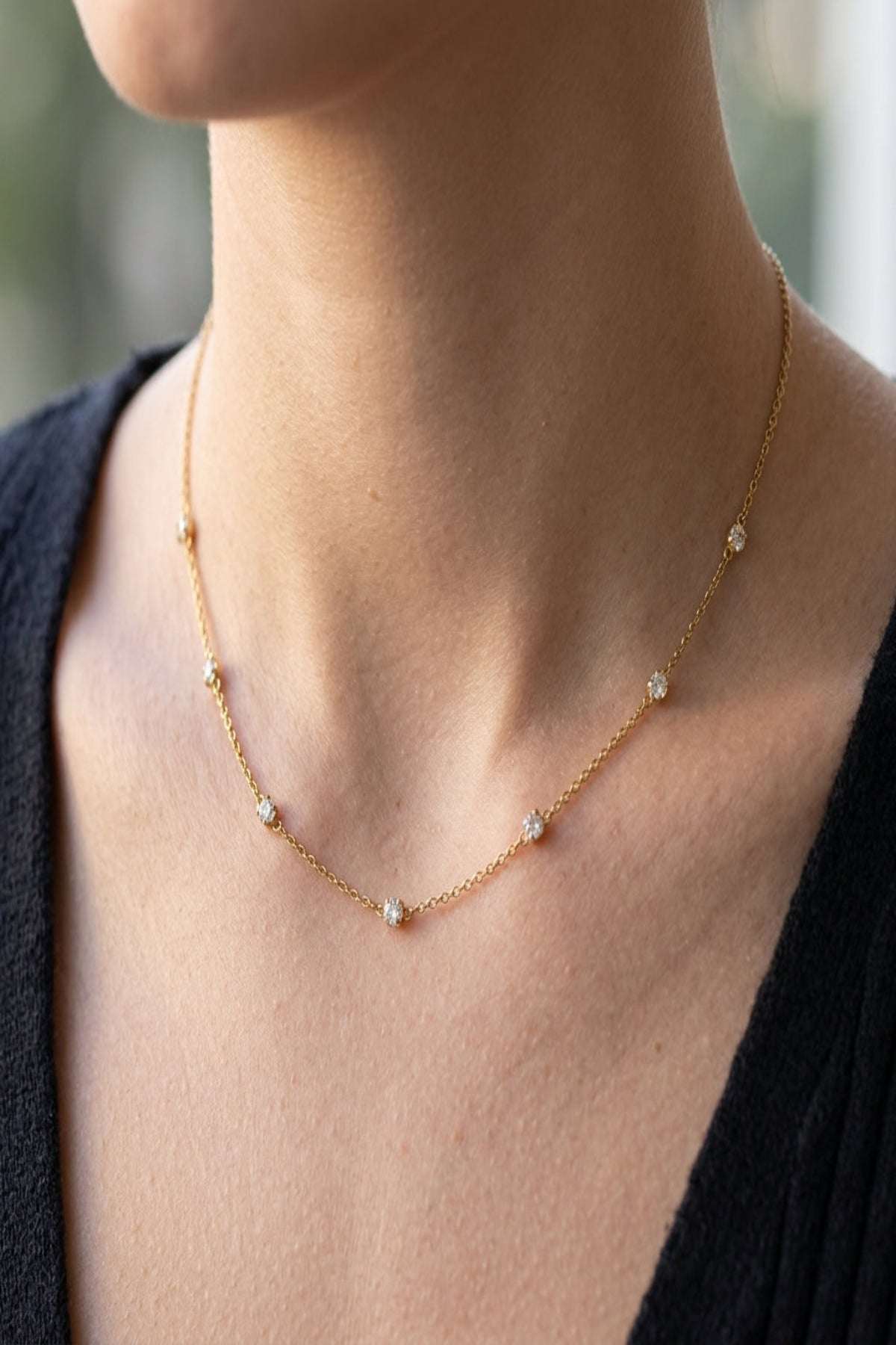 Close-up of diamond whisper necklace showcasing its stainless steel chain and rhinestone accents on a model's neck with soft natural lighting.