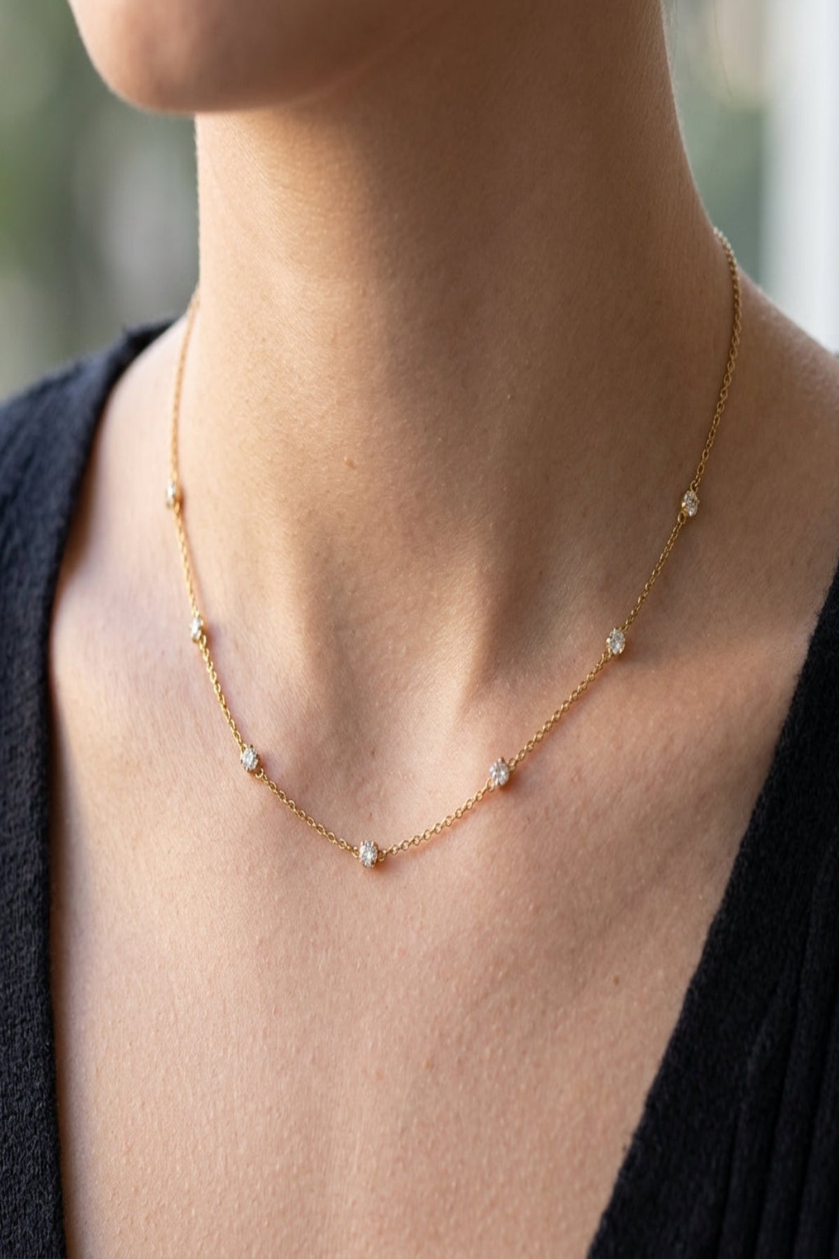 Close-up of diamond whisper necklace showcasing its stainless steel chain and rhinestone accents on a model's neck with soft natural lighting.