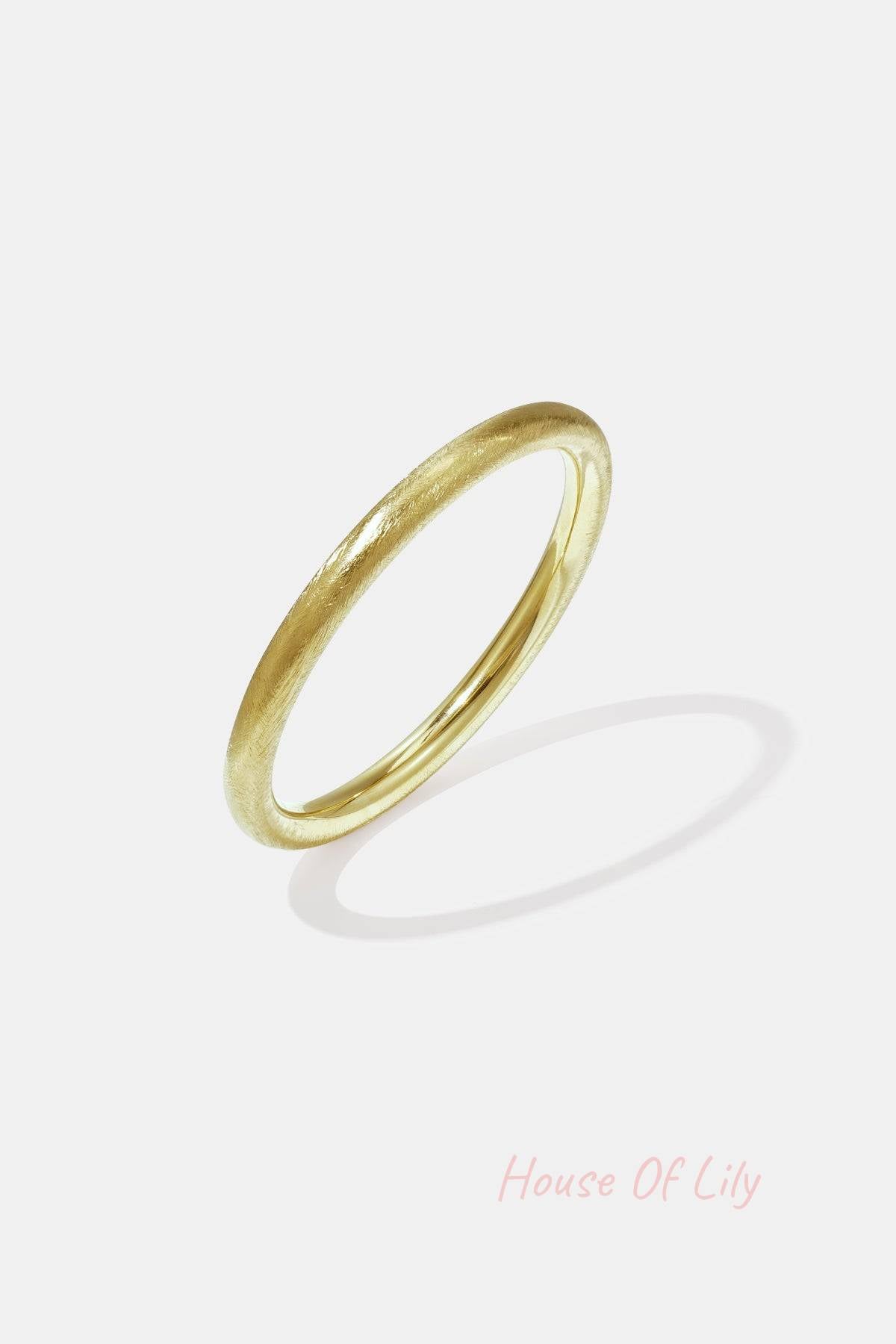 Gold minimalist bangle bracelet with a brushed texture on white background