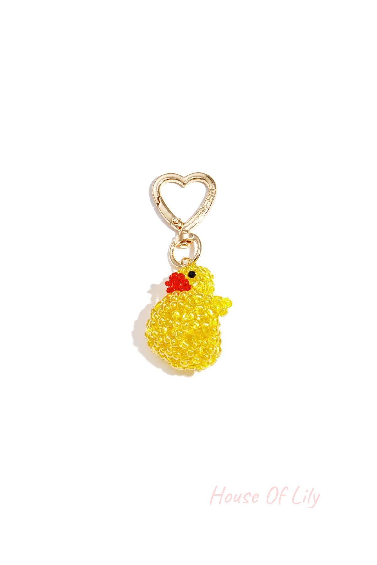 Close-up of a beaded yellow duck charm with orange beak attached to a gold heart-shaped clasp.
