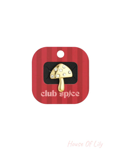 Gold mushroom pin with crystal accents, displayed on a red and white striped backing.