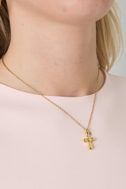 Close-up of woman wearing the gold cross pendant necklace styled with soft pink top