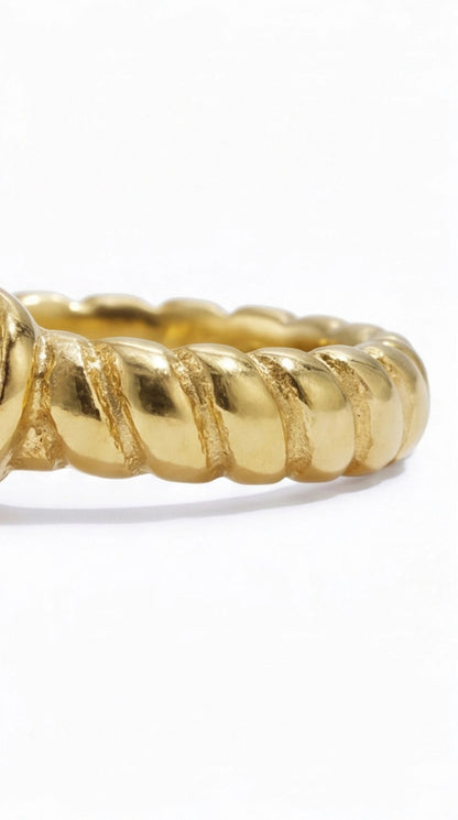 Gold ring with a textured design on a white background