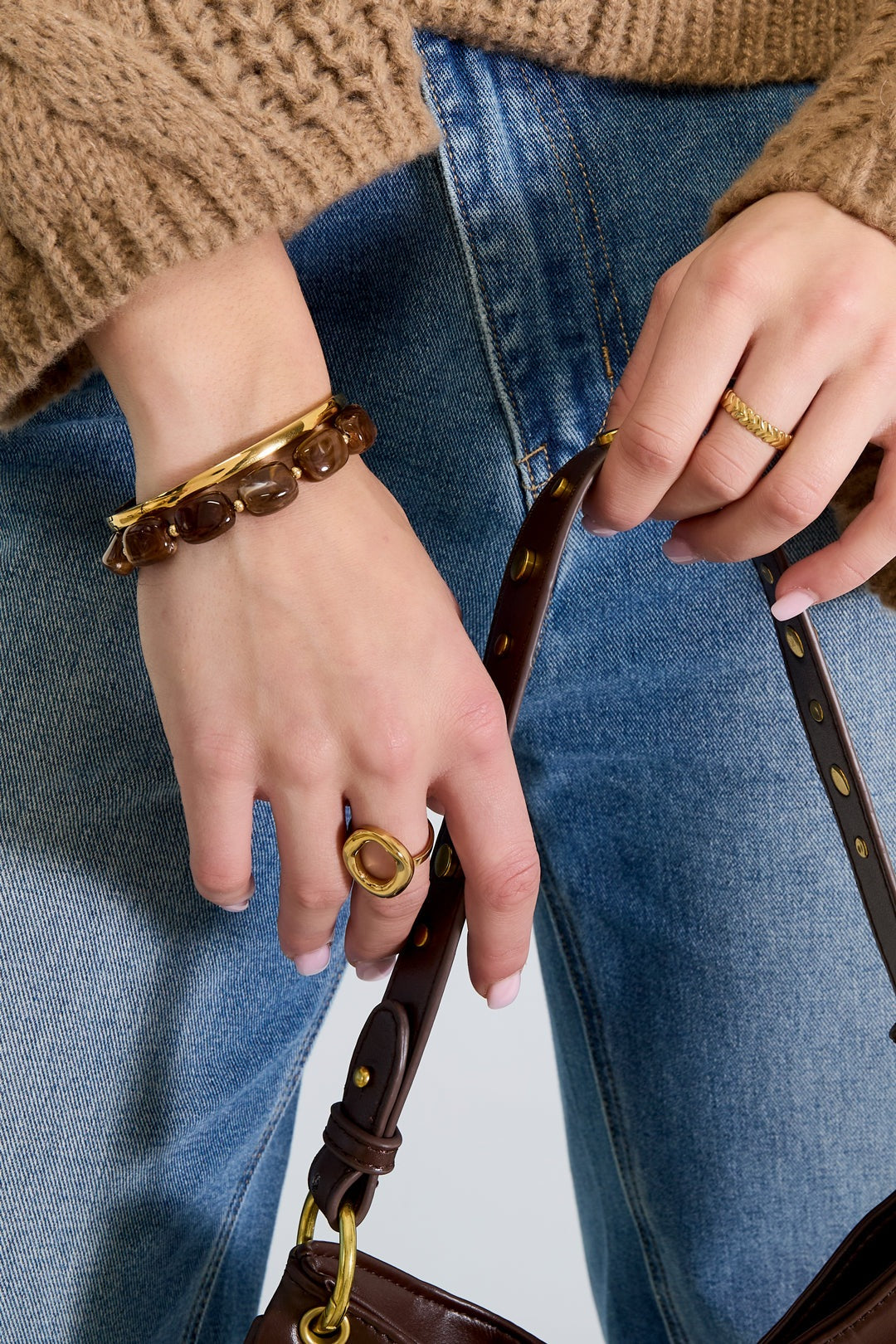 Model showing chocolate brown acrylic beaded bracelet with gold ring and brown handbag strap