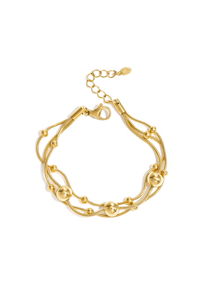 Gold multi-strand chain bracelet with polished round beads and adjustable lobster clasp on white background