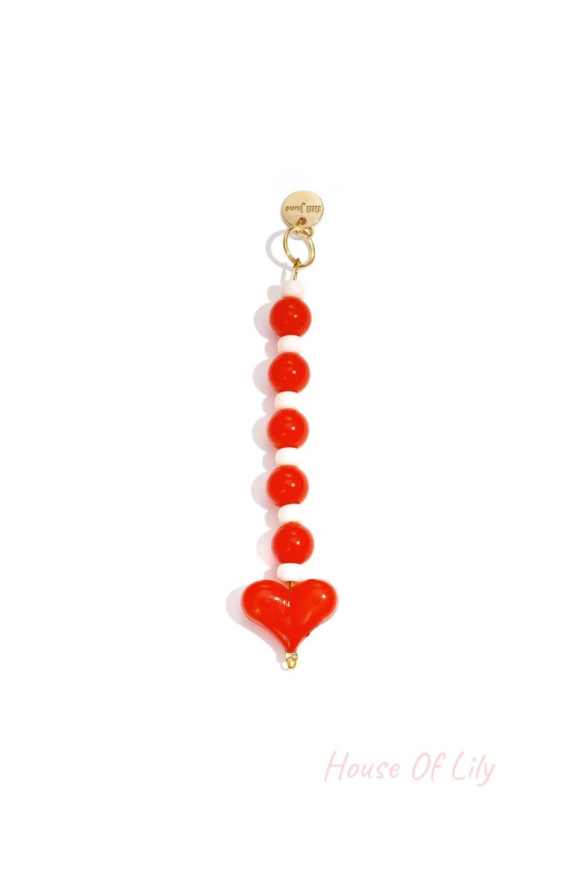 Red and white heart bead bag charm with gold clasp on white background