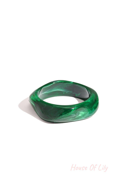 Single deep green marbled acrylic wavy square bangle on a white background