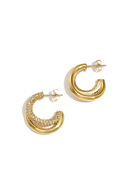 Pair of chunky gold tone hoop earrings with rhinestone detail on white background