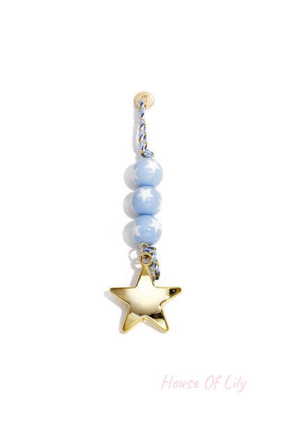 Pastel blue star bead charm with gold star pendant and braided cord on white background