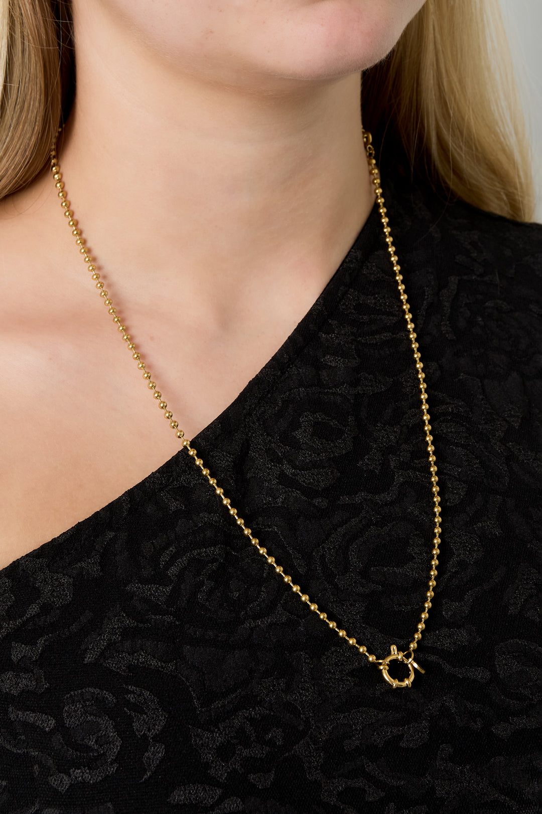 Model wearing gold bead chain necklace with toggle clasp in front over black top