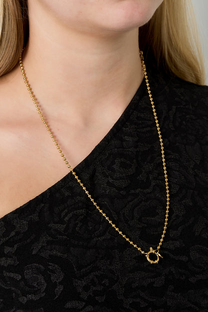 Model wearing gold bead chain necklace with toggle clasp in front over black top