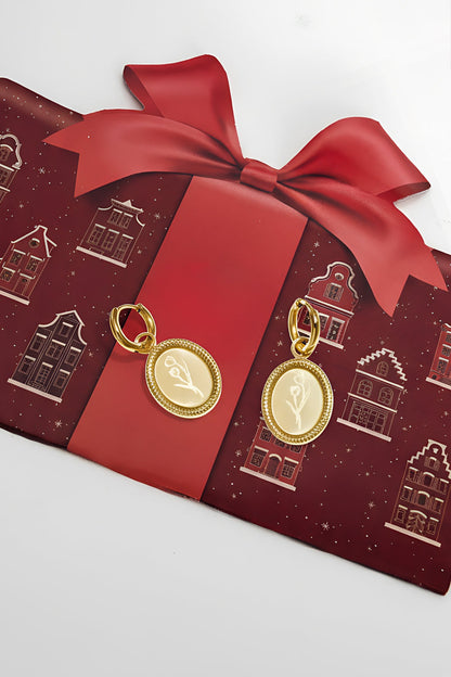 Gold floral oval hoop earrings on red gift wrap with large ribbon bow