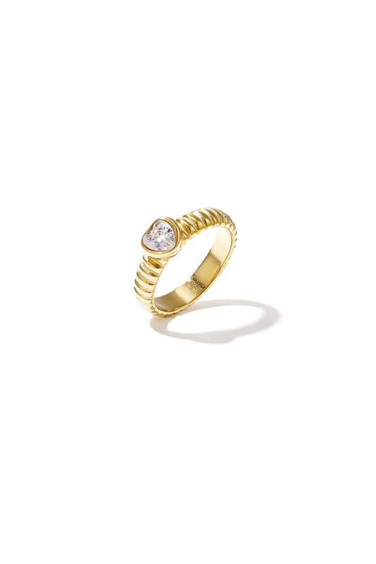 Gold-tone ring with a heart-shaped clear zircon stone and textured band on white background