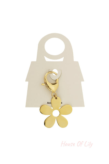 Shiny gold-tone flower charm with a circular center cut-out, attached to a lobster clasp on a display card.