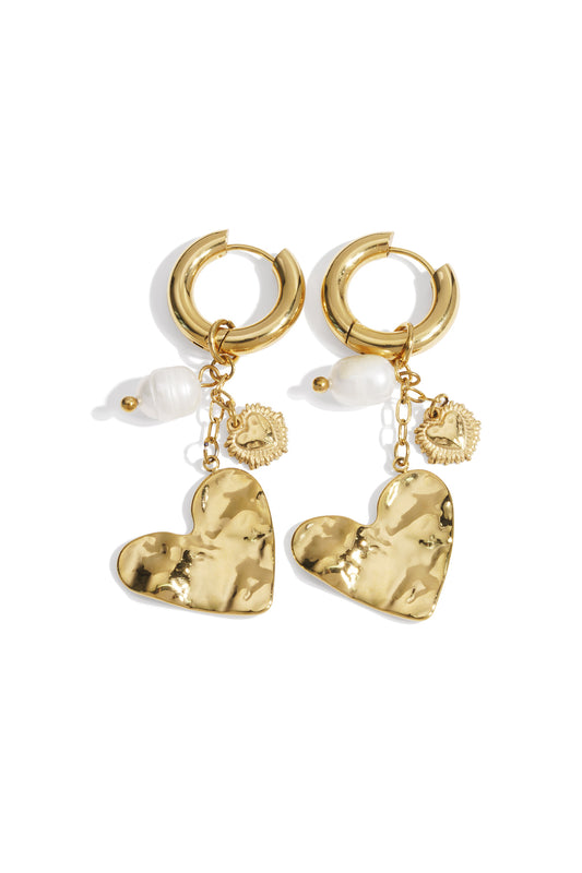 Gold hoop earrings with hammered heart charms, pearl accents, and small heart dangles on white background