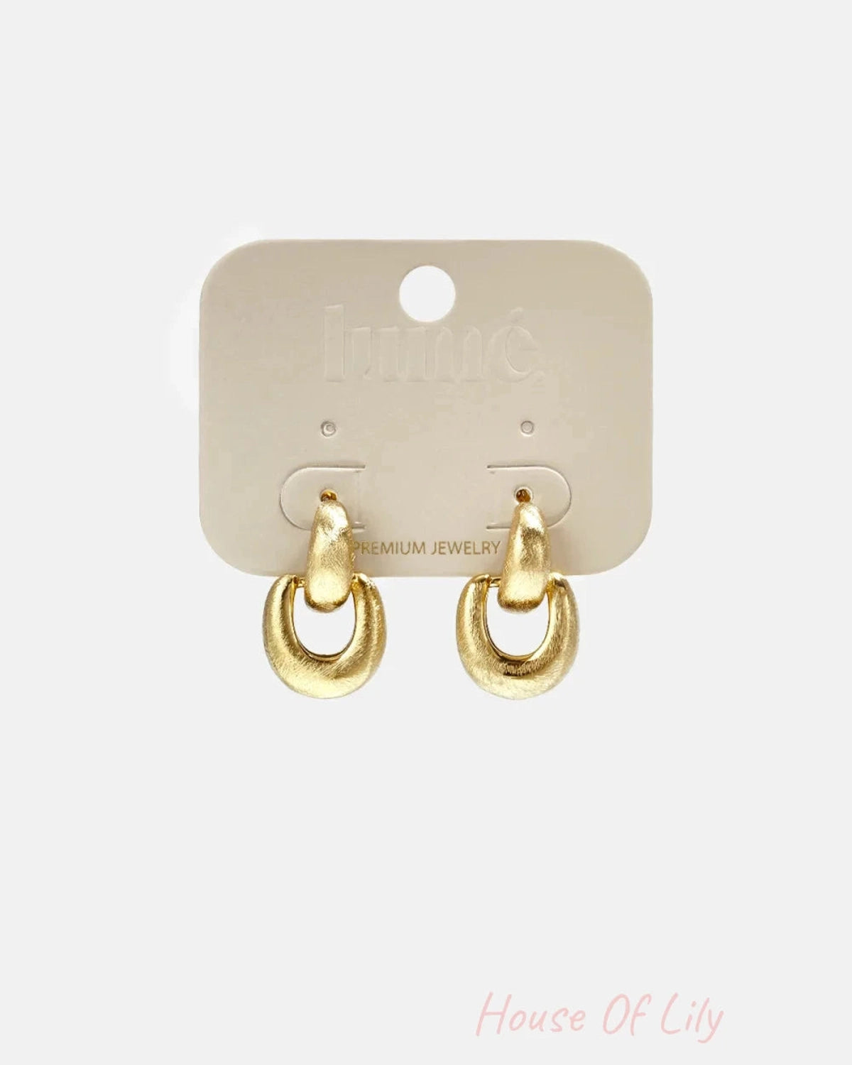 A pair of brushed gold drop earrings mounted on a beige card display.