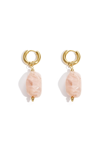 Gold hoop earrings with irregular off-white resin drop beads on white background