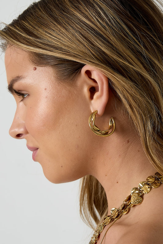 Side view of woman wearing gold twisted double hoop earring