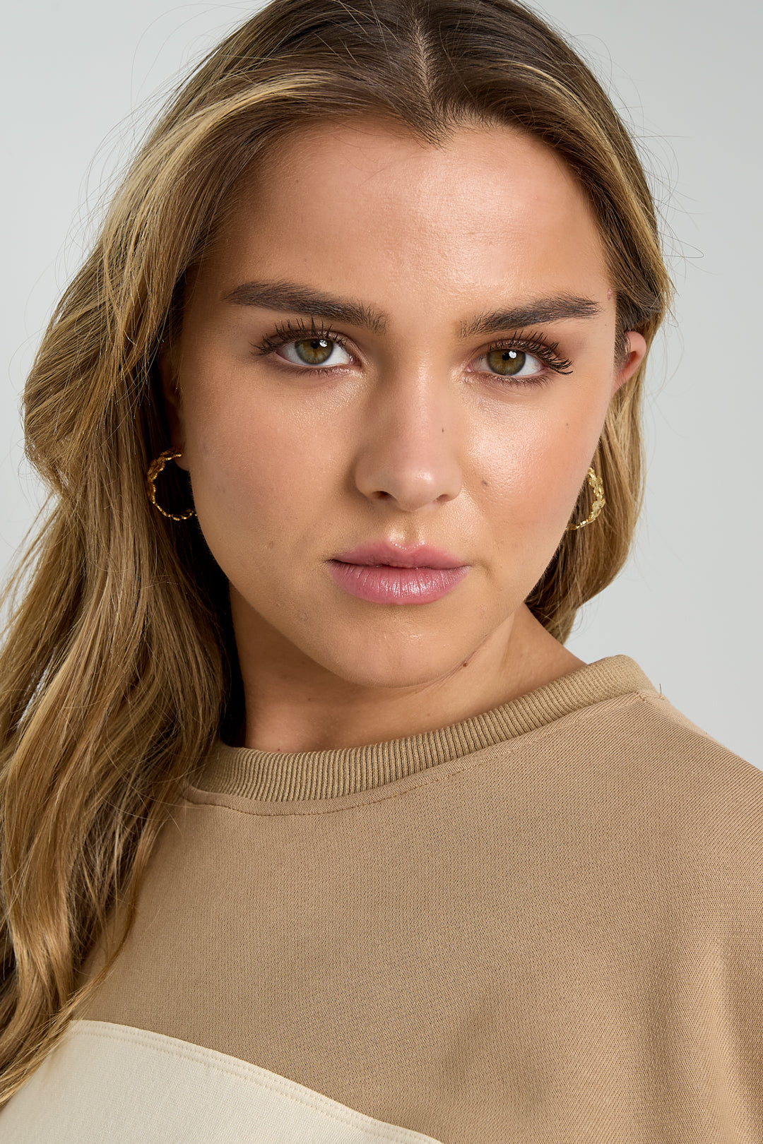 Close-up of a woman wearing gold floral hoop earrings, showcasing their delicate design and youthful aesthetic.