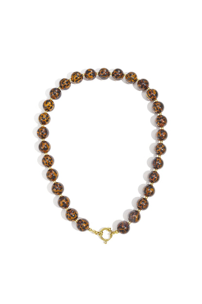 Close-up of a leopard print beaded necklace with small gold spacer beads and gold clasp on white background