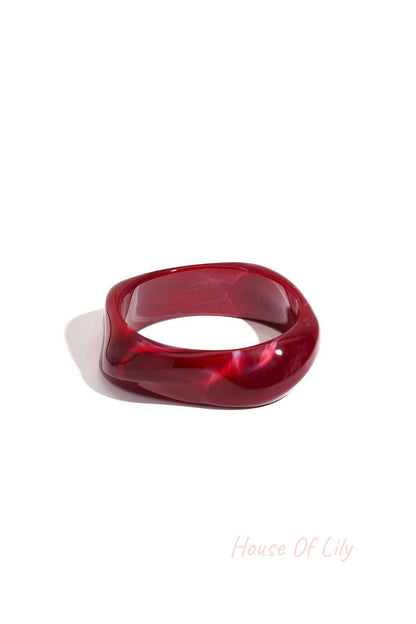 Single deep burgundy acrylic wavy square bangle on a white background