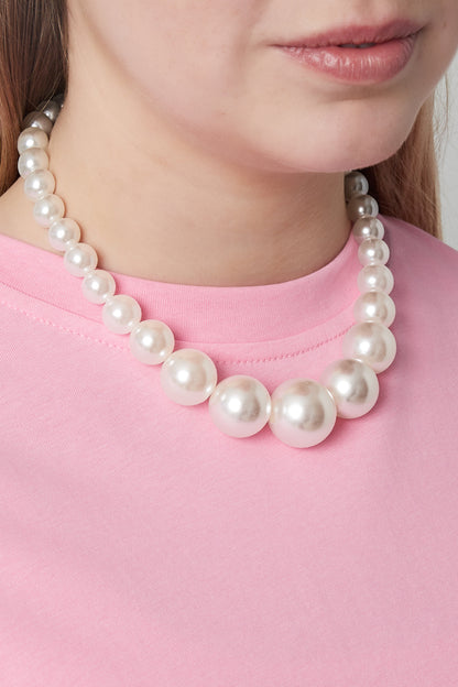 Woman wearing a graduated pearl beaded necklace paired with a pink top, highlighting the necklace's soft and elegant look