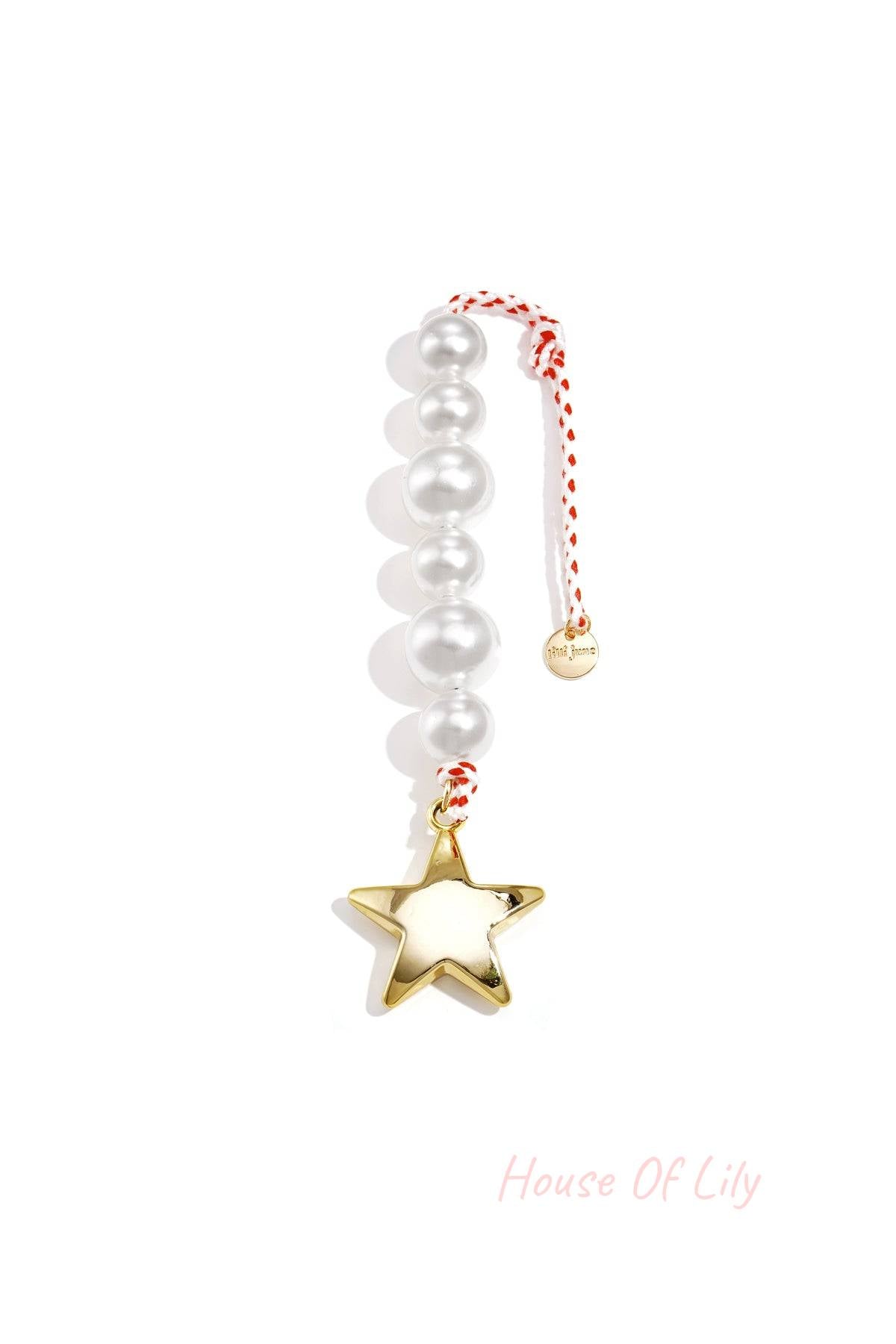 Close-up of a pearl star bag charm with white acrylic beads, gold star pendant, and red-white braided rope on a white background