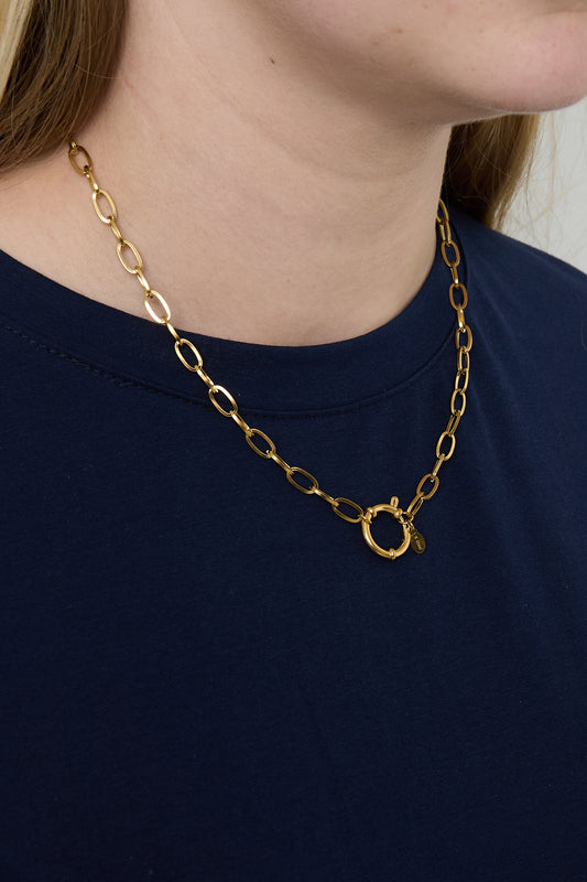 Model wearing gold link chain necklace with toggle clasp on navy blue shirt, side view