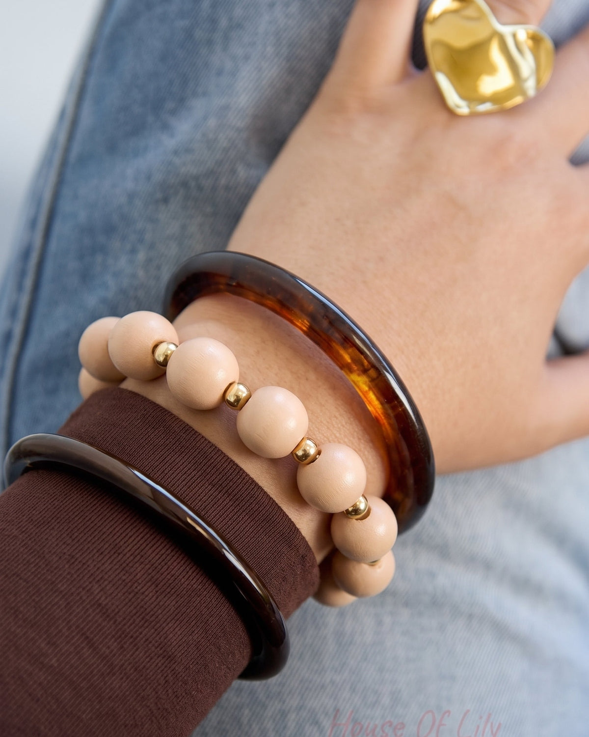 Pink Beaded Bracelet features smooth pink beads separated by small gold spheres, worn with resin bangles.