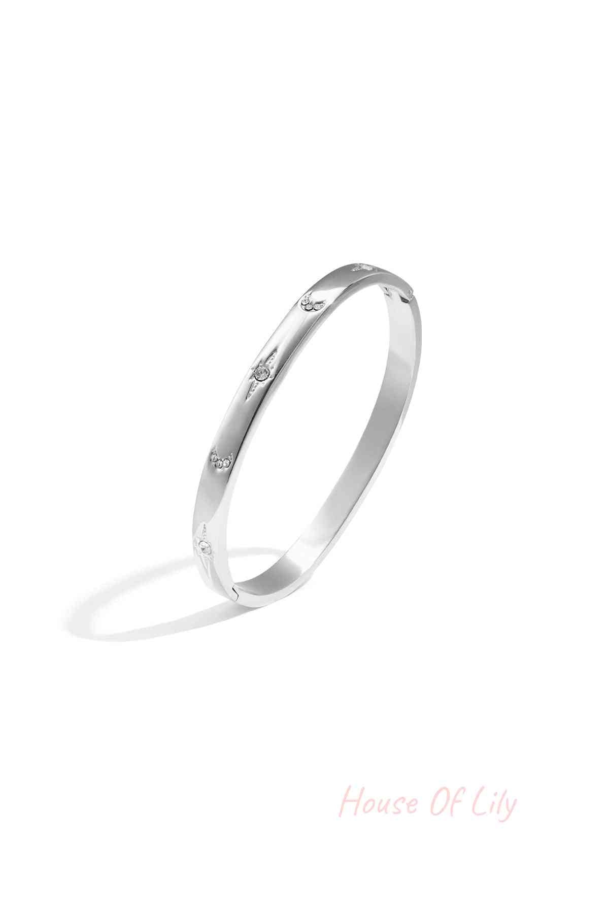 Silver-tone slim metal bangle bracelet with crystal star and crescent accents on white background