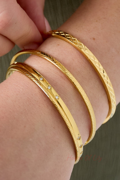 Model wearing three gold bangles stacked together, including the mini diamond design