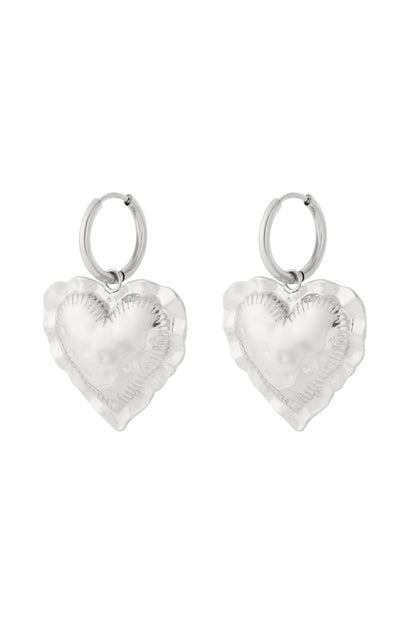 Pair of silver tone heart drop hoop earrings with hammered texture on white background