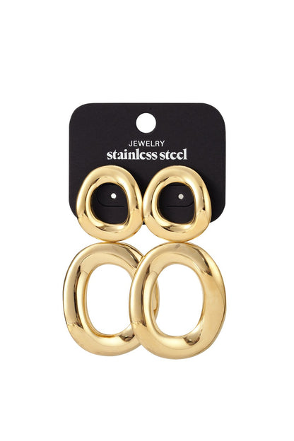 Main Character Twist Hoops: Gold-tone, twisted oval stainless steel earrings on a black display card.