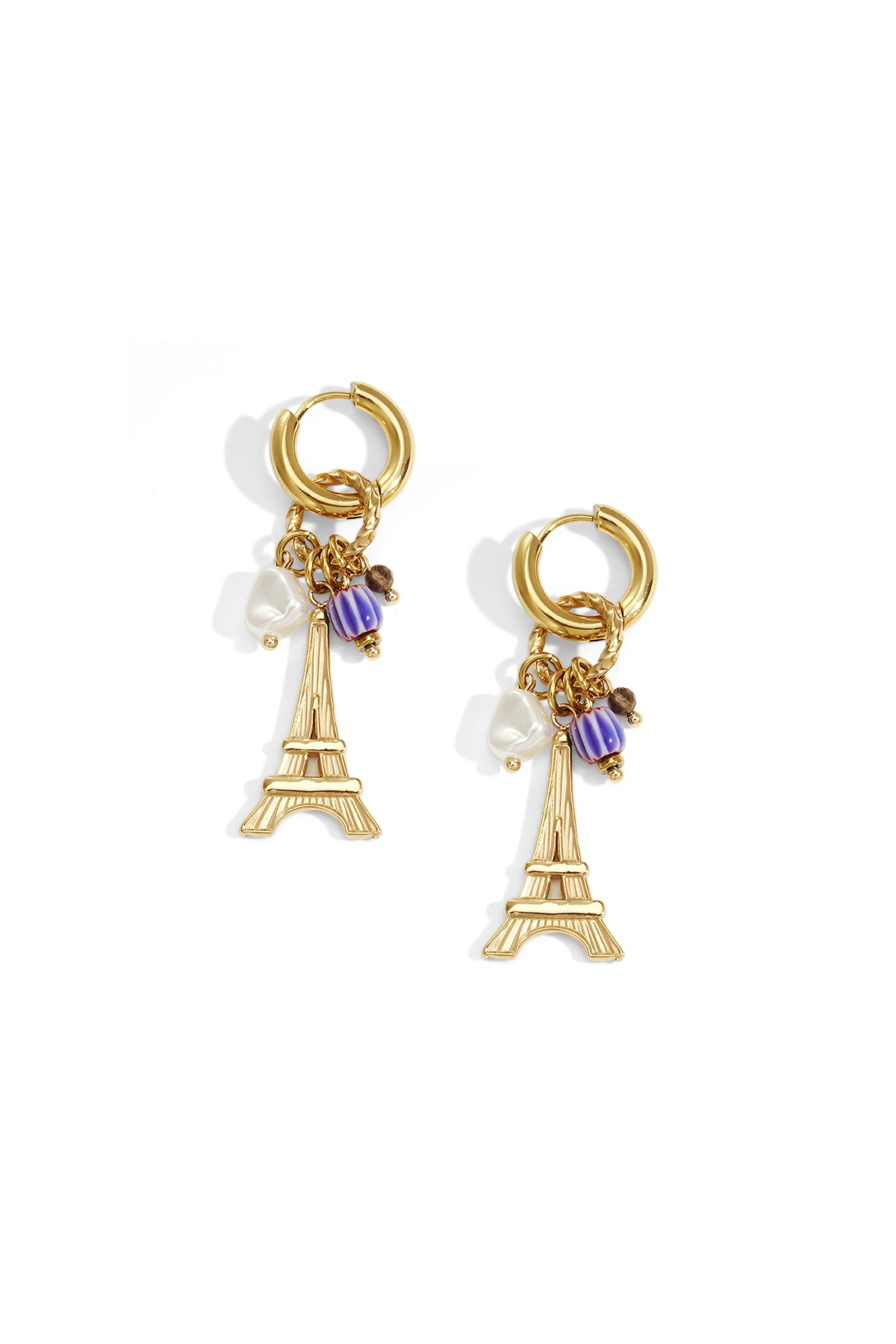 Gold-tone hoop earrings with dangling Eiffel Tower charm, white pearl-shaped bead, and purple accent bead on white background