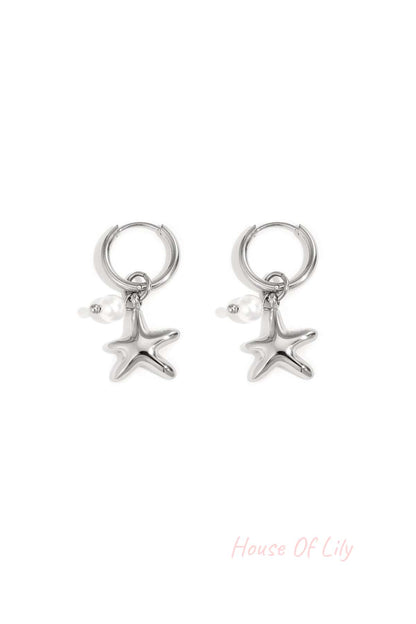 Pair of silver starfish charm hoop earrings with small pearl detail on white background