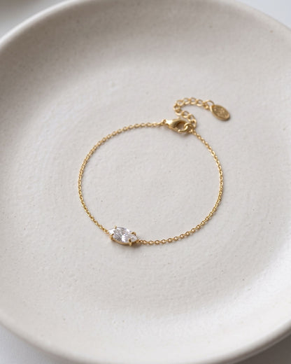 Elegant ellipse rhinestone charm bracelet displayed on a textured matte ceramic dish.