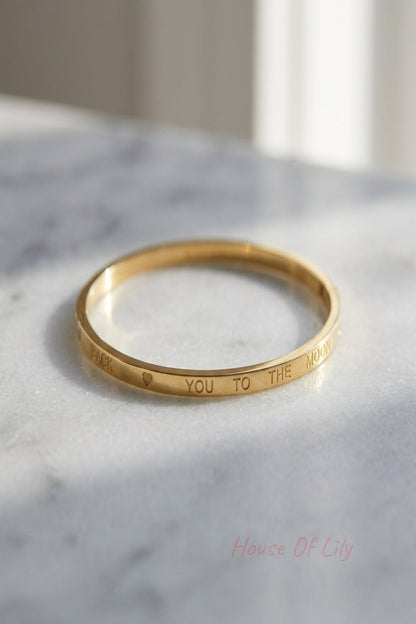 Small women's bracelet with minimalist design, displayed on a reflective surface with natural lighting and delicate lettering.