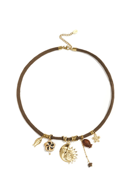 Close-up of brown rope necklace with gold sun and moon pendant and various whimsical charms on white background