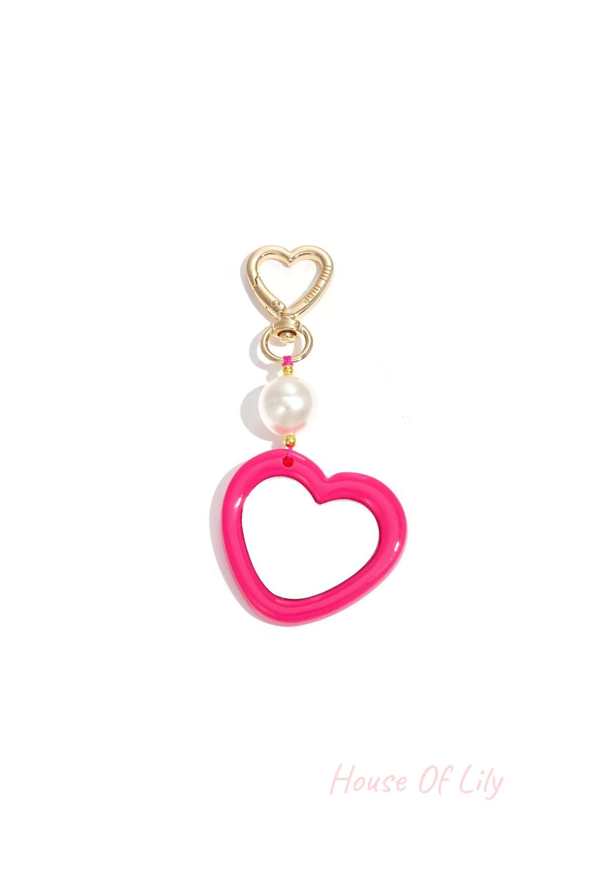 Gold clip with pink acrylic heart charm and pearl bead close-up on white background