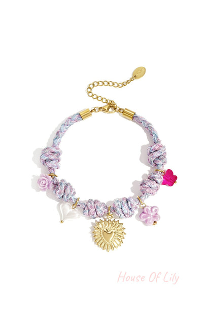 Lavender and blue twisted rope charm bracelet with a gold sunburst heart charm and assorted floral and heart-shaped pastel charms