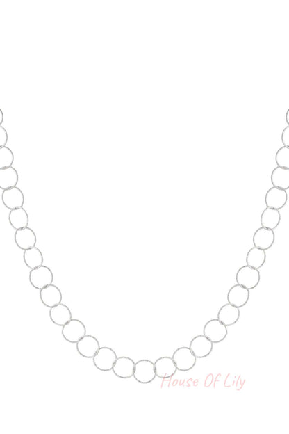 Close-up of textured loop chain necklace in silver tone on white background