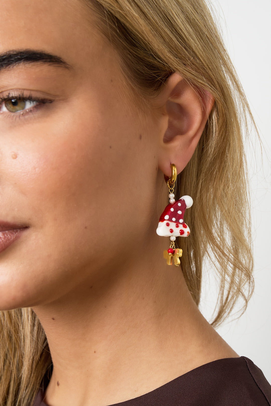 Close-up side view of a different angle showing the festive Santa hat drop earring on a woman's ear highlighting color and texture.